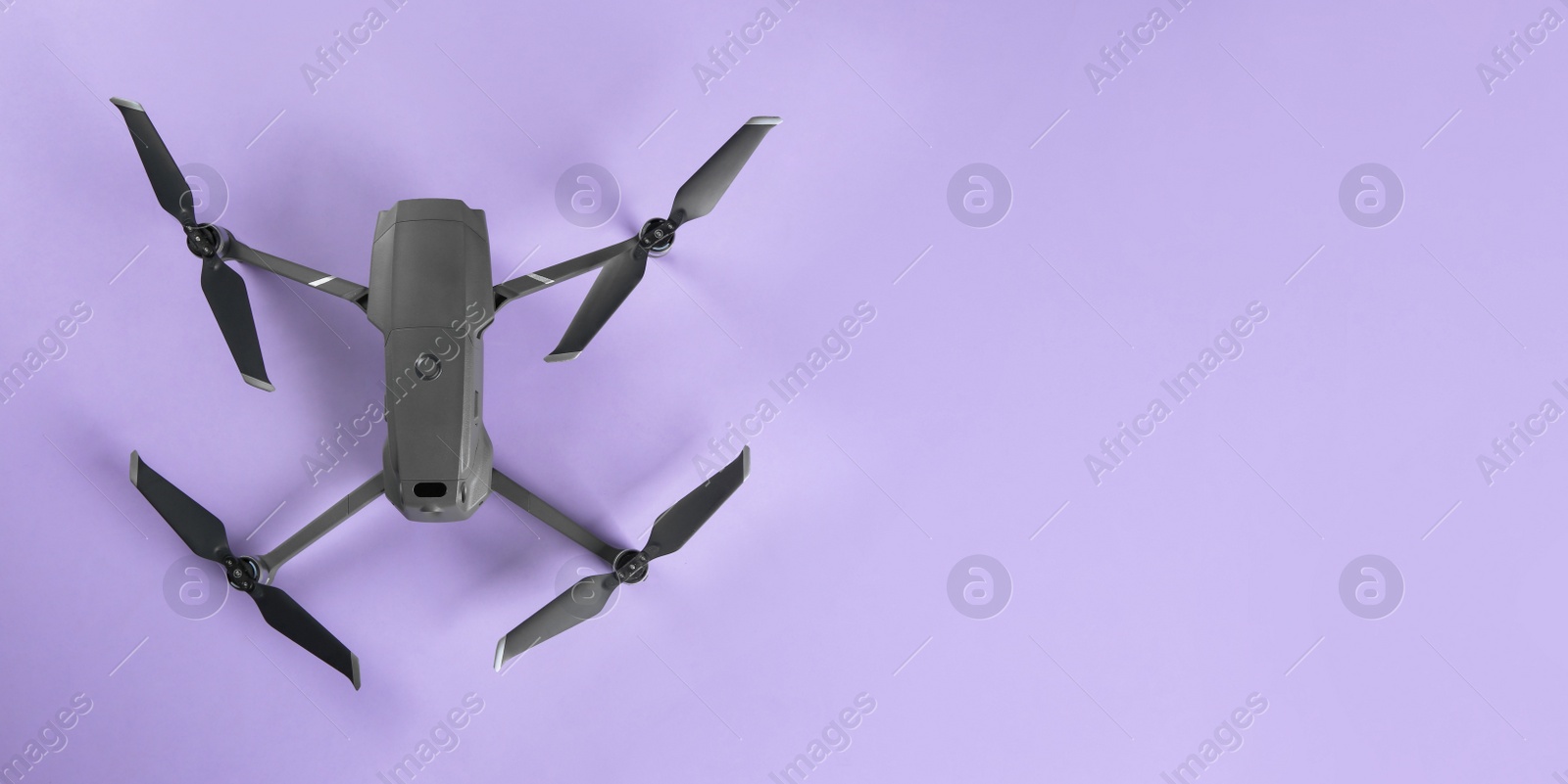 Photo of Modern drone with camera on lilac background, top view. Space for text