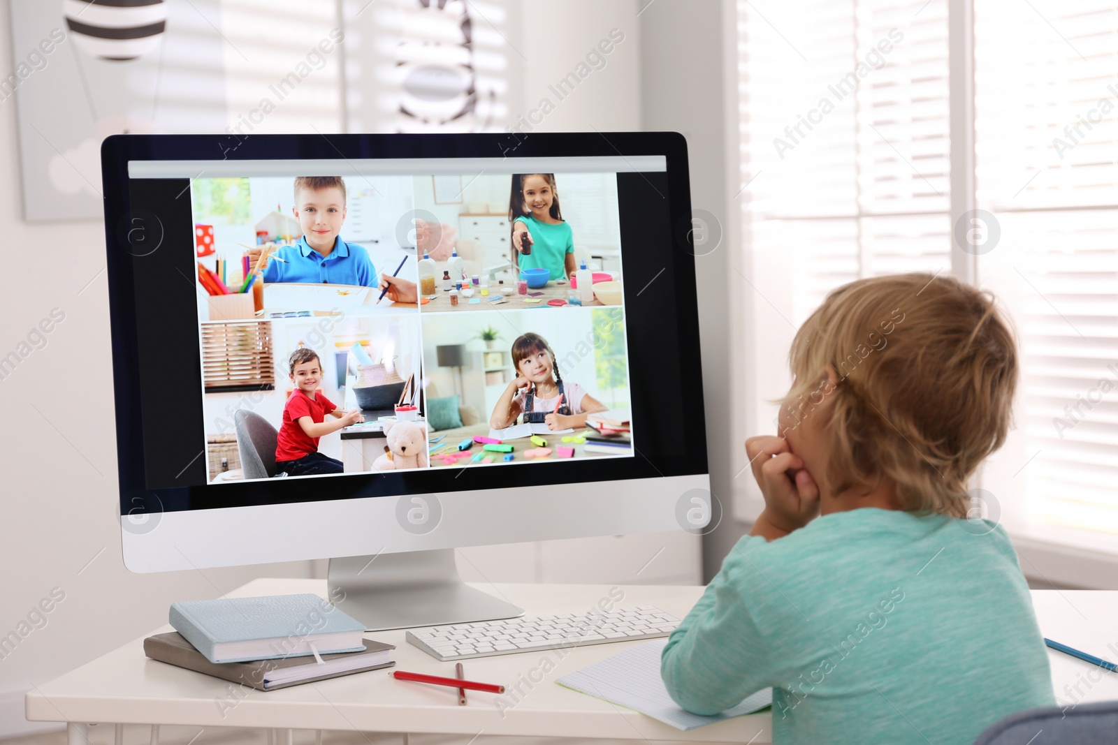 Photo of Little boy studying with classmates via video conference at home. Distance learning during COVID-19 pandemic