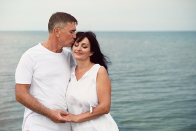 Photo of Happy mature couple spending time together on sea beach. Space for text