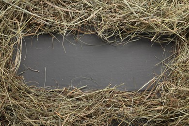 Photo of Frame made of dried hay on grey wooden table, top view. Space for text