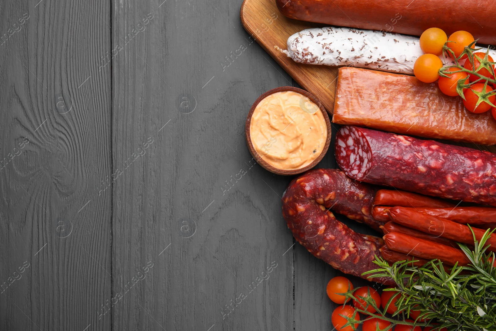 Photo of Different types of tasty sausages on grey wooden table, flat lay. Space for text