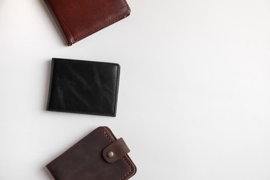 Leather wallets on light background, flat lay. Space for text