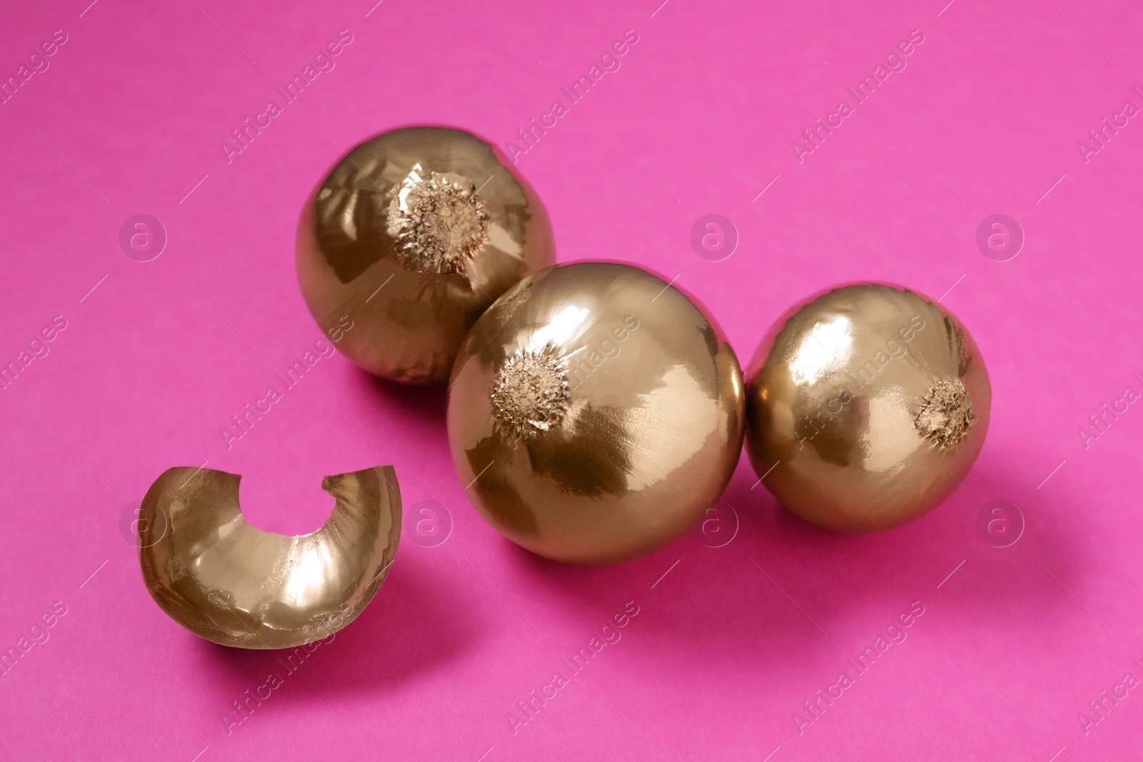 Photo of Pile of golden onions on pink background