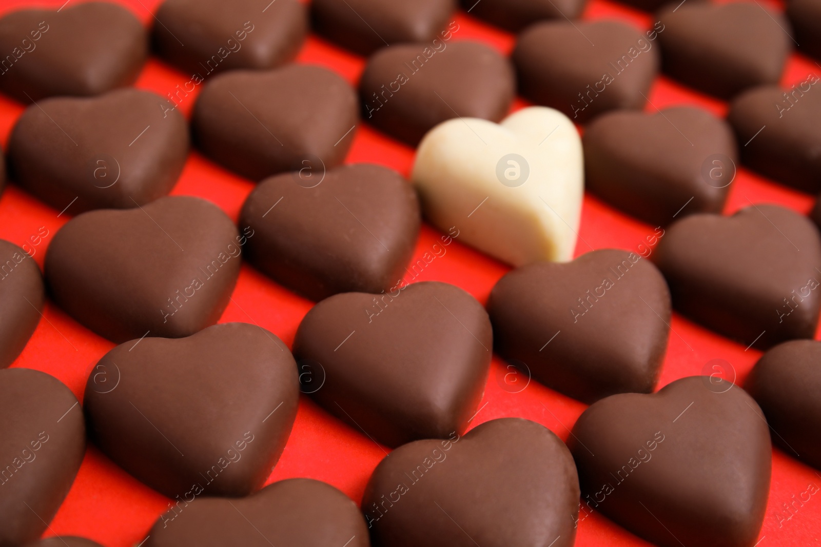 Photo of Tasty heart shaped chocolate candies on red background, closeup. Happy Valentine's day