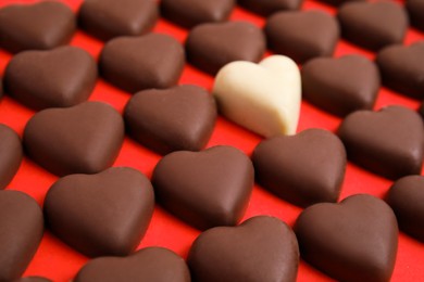Photo of Tasty heart shaped chocolate candies on red background, closeup. Happy Valentine's day