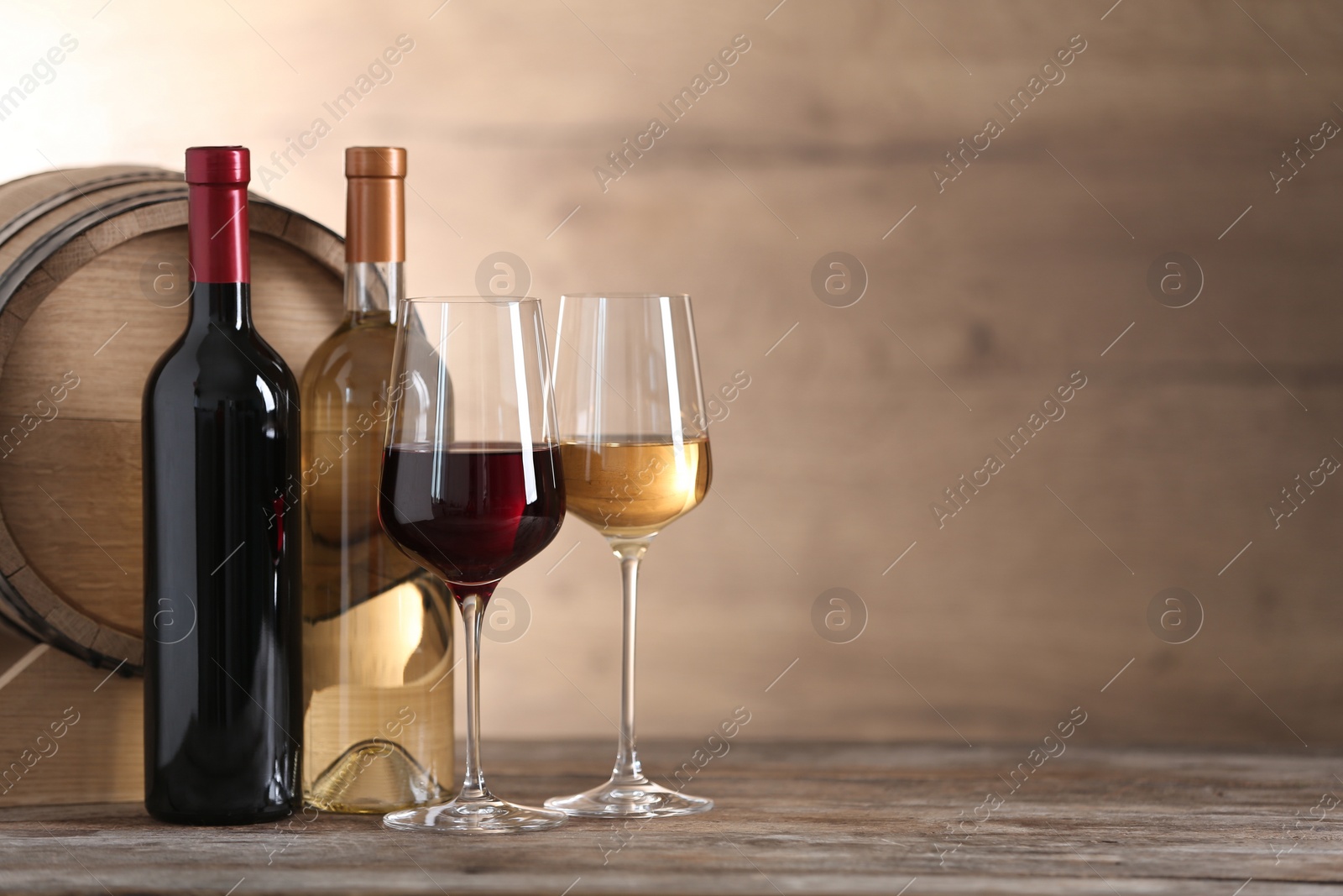 Photo of Glasses and bottles of different wine near wooden barrel on table. Space for text