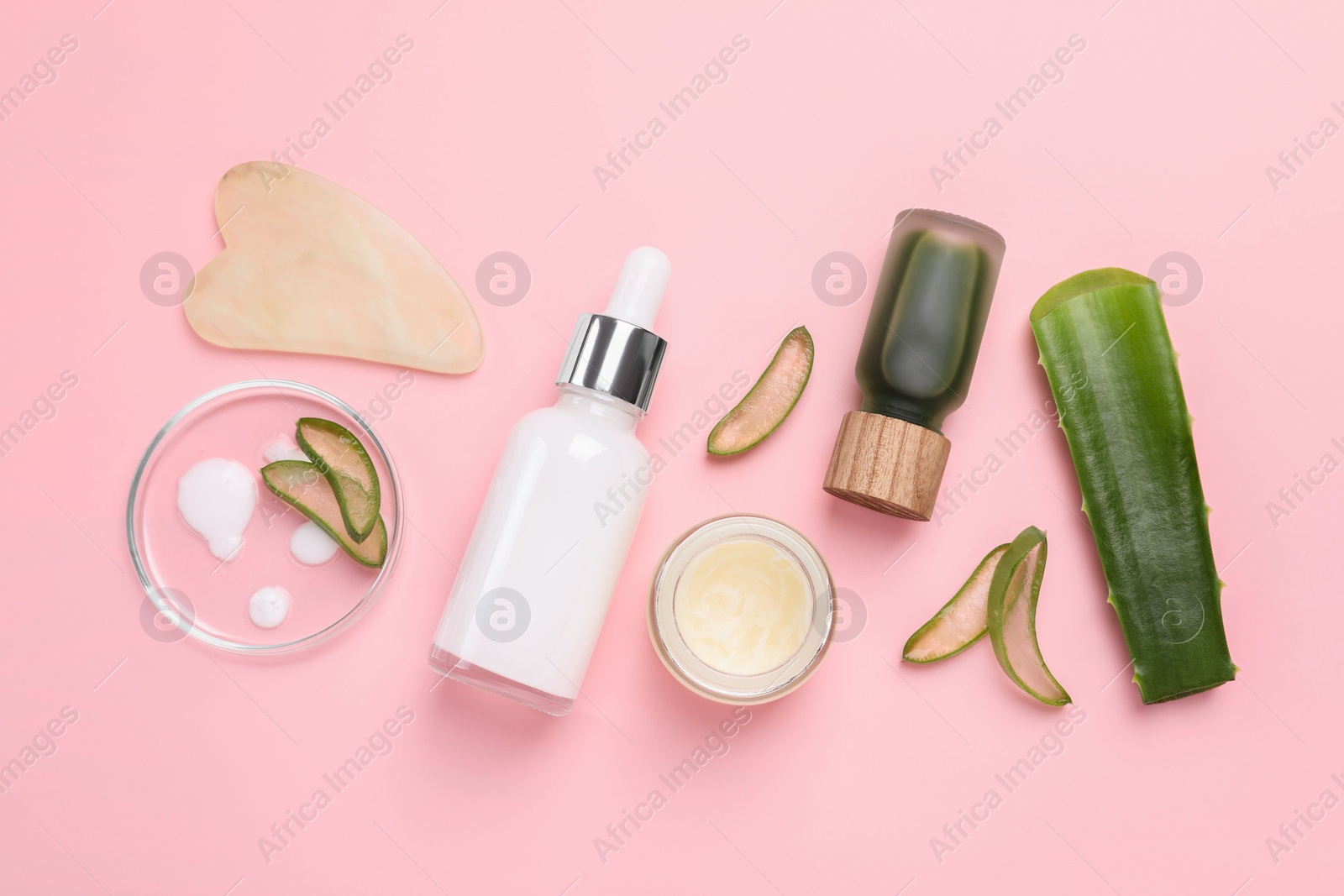 Photo of Cosmetic products, cut aloe leaves and gua sha tool on pink background, flat lay