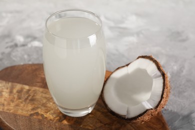 Glass of coconut water and nut on grey table