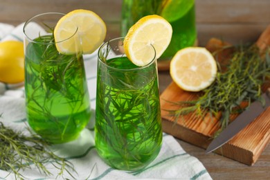 Photo of Glasses of refreshing tarragon drink with lemon slices on table