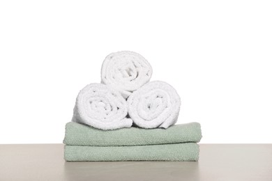 Photo of Soft colorful terry towels on light table against white background