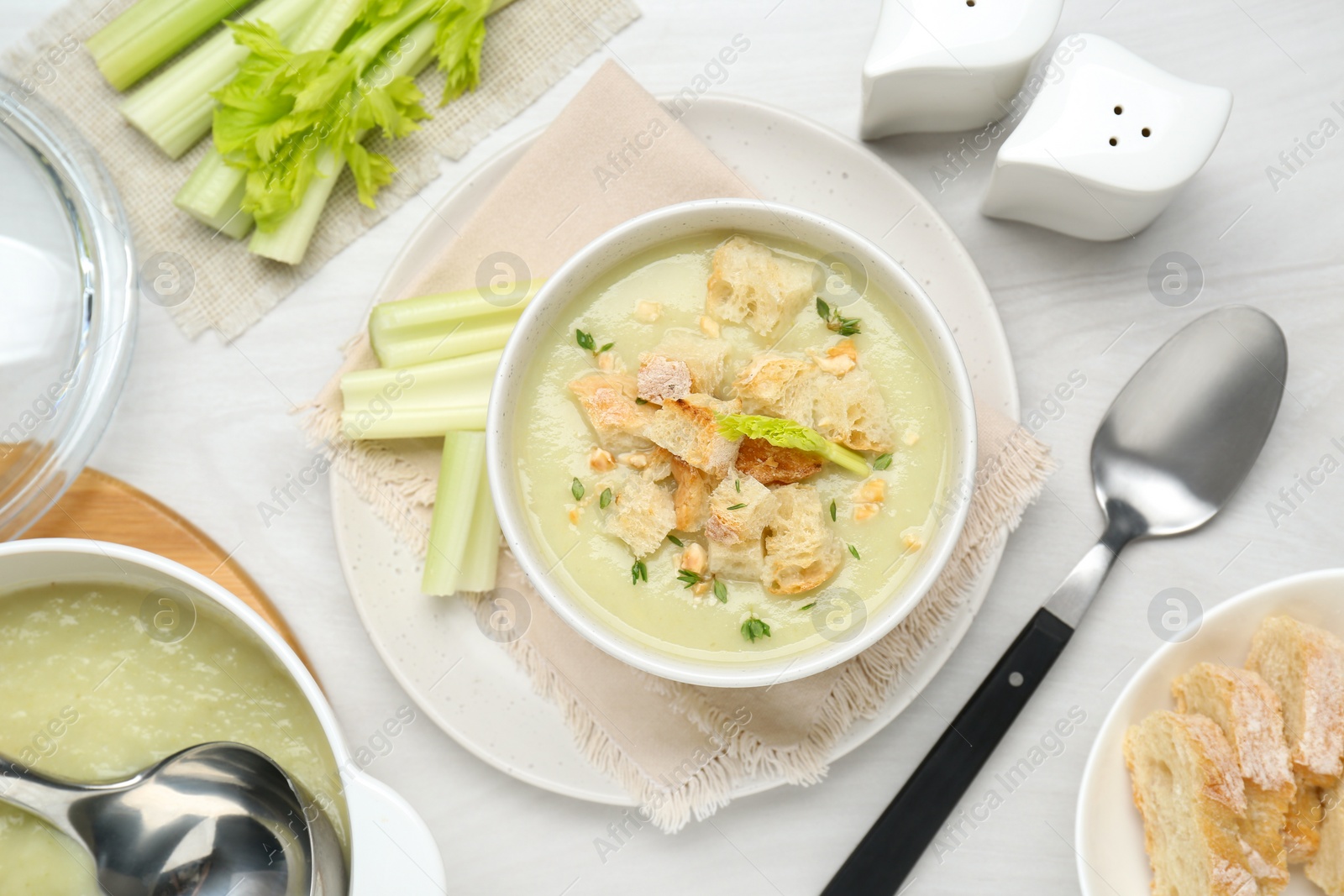 Photo of Delicious celery soup served on white wooden table, flat lay