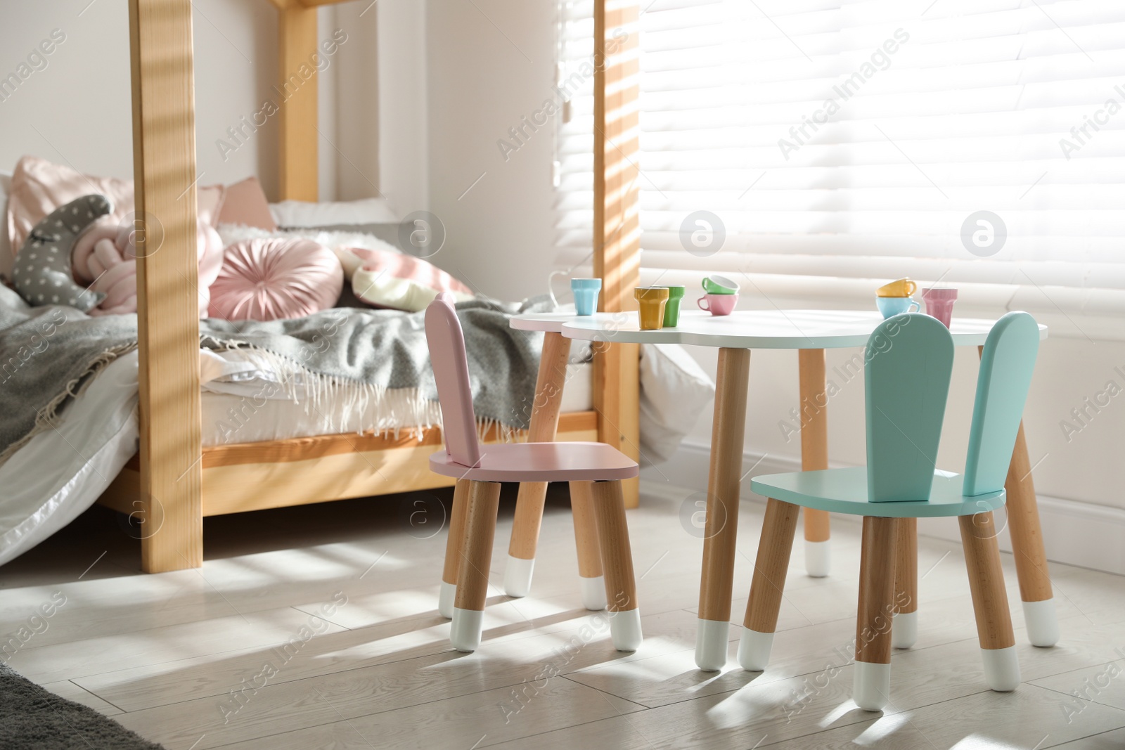 Photo of Small table and chairs with bunny ears in children's bedroom interior