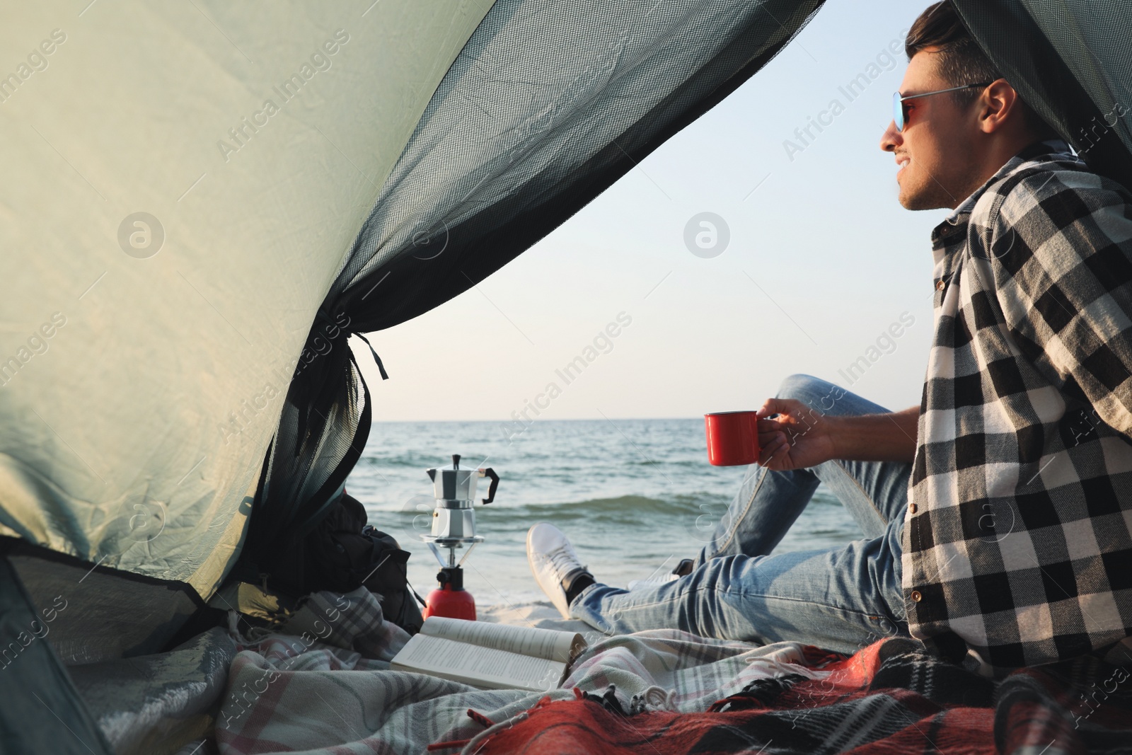 Photo of Man with cup of hot drink in camping tent