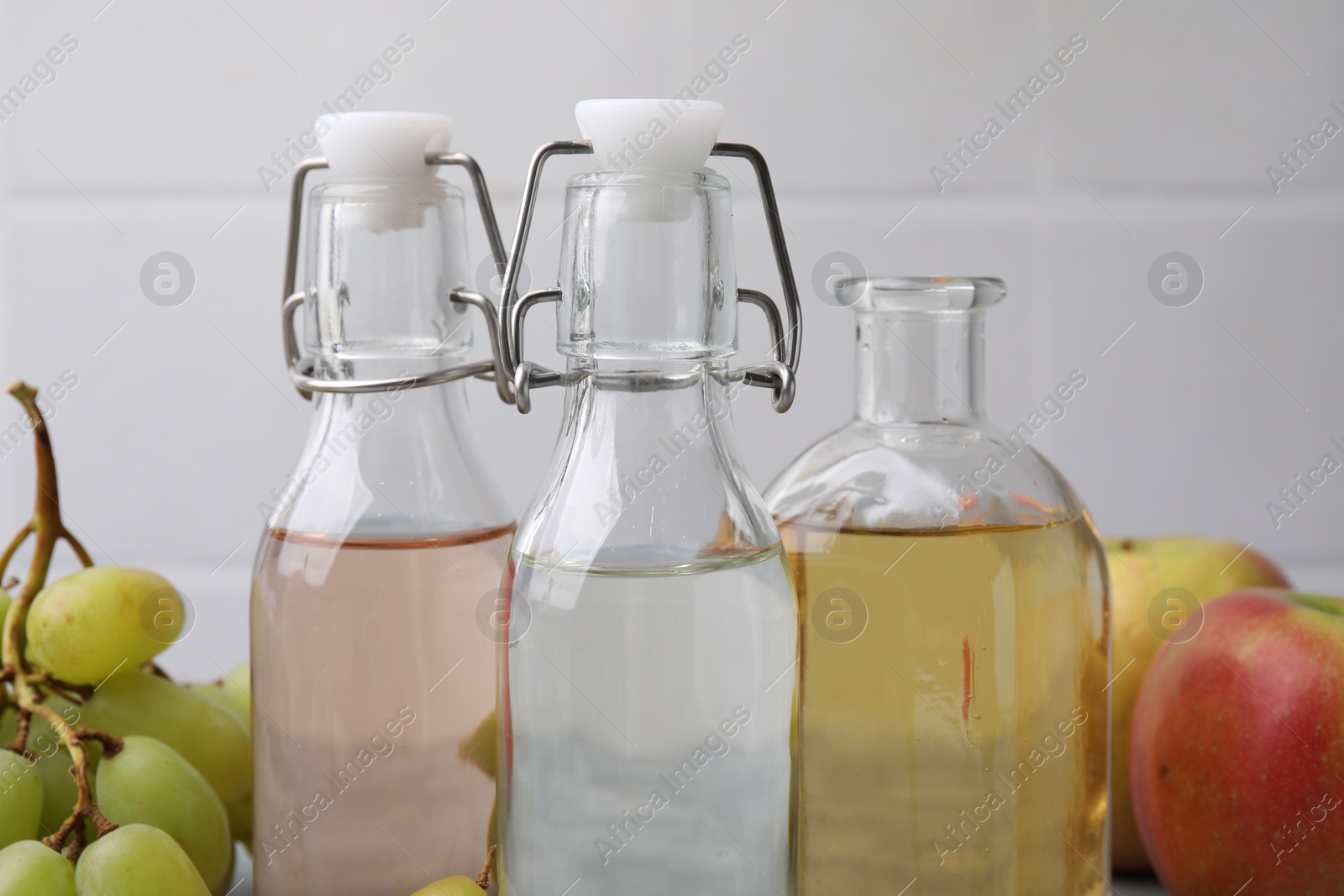 Photo of Different types of vinegar and fresh fruits on table