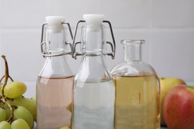 Photo of Different types of vinegar and fresh fruits on table