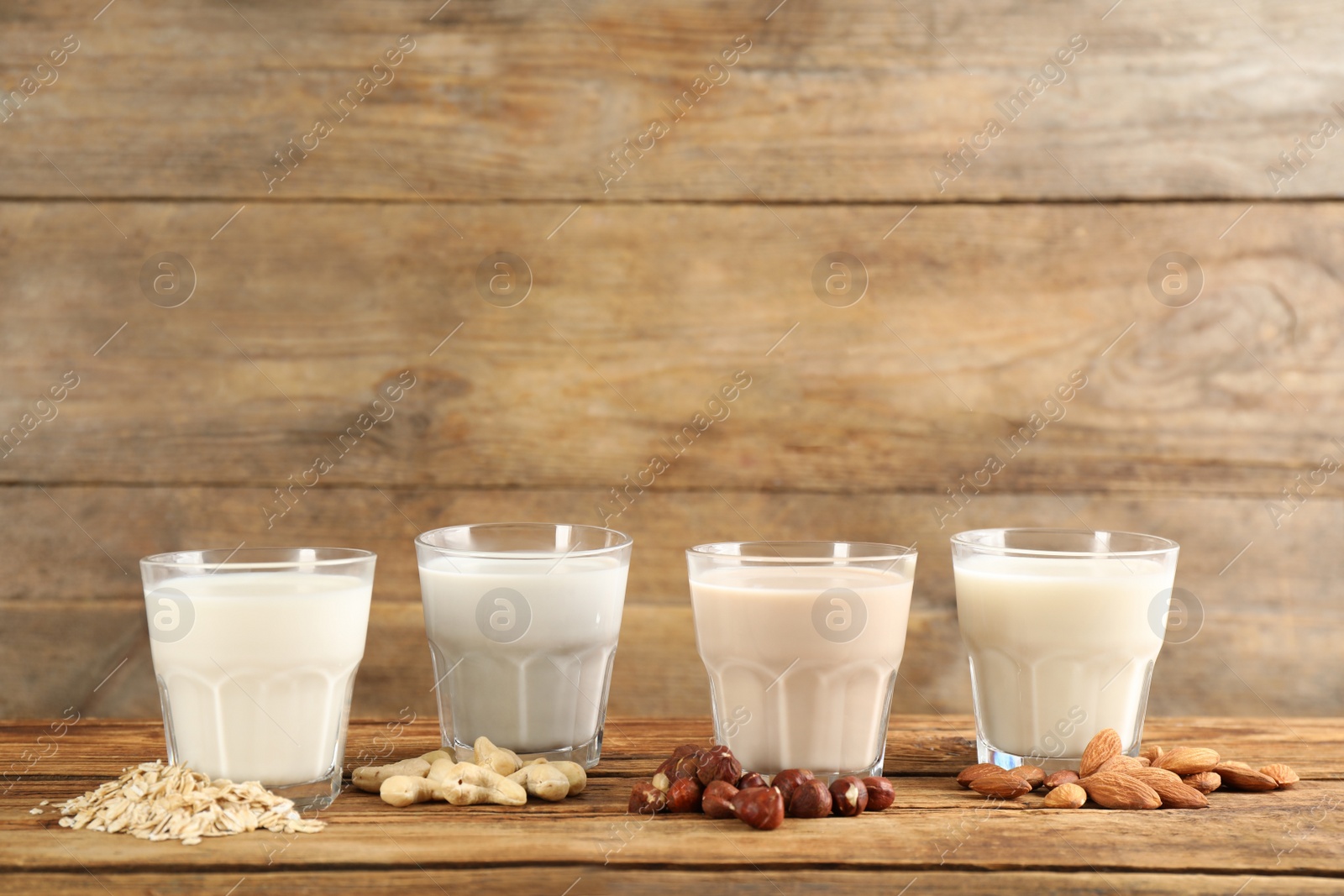 Photo of Different vegan milks and ingredients on wooden table. Space for text