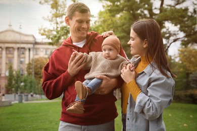 Photo of Happy parents with their adorable baby walking in park