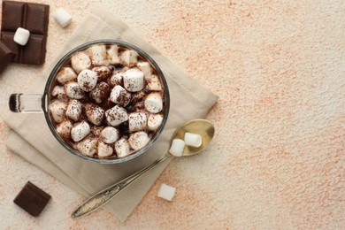 Cup of aromatic hot chocolate with marshmallows and cocoa powder served on beige table, flat lay. Space for text