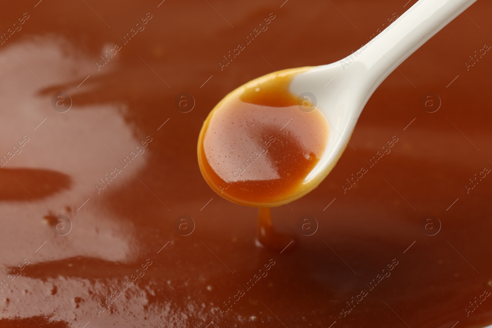 Photo of Taking tasty salted caramel with spoon, closeup. Space for text