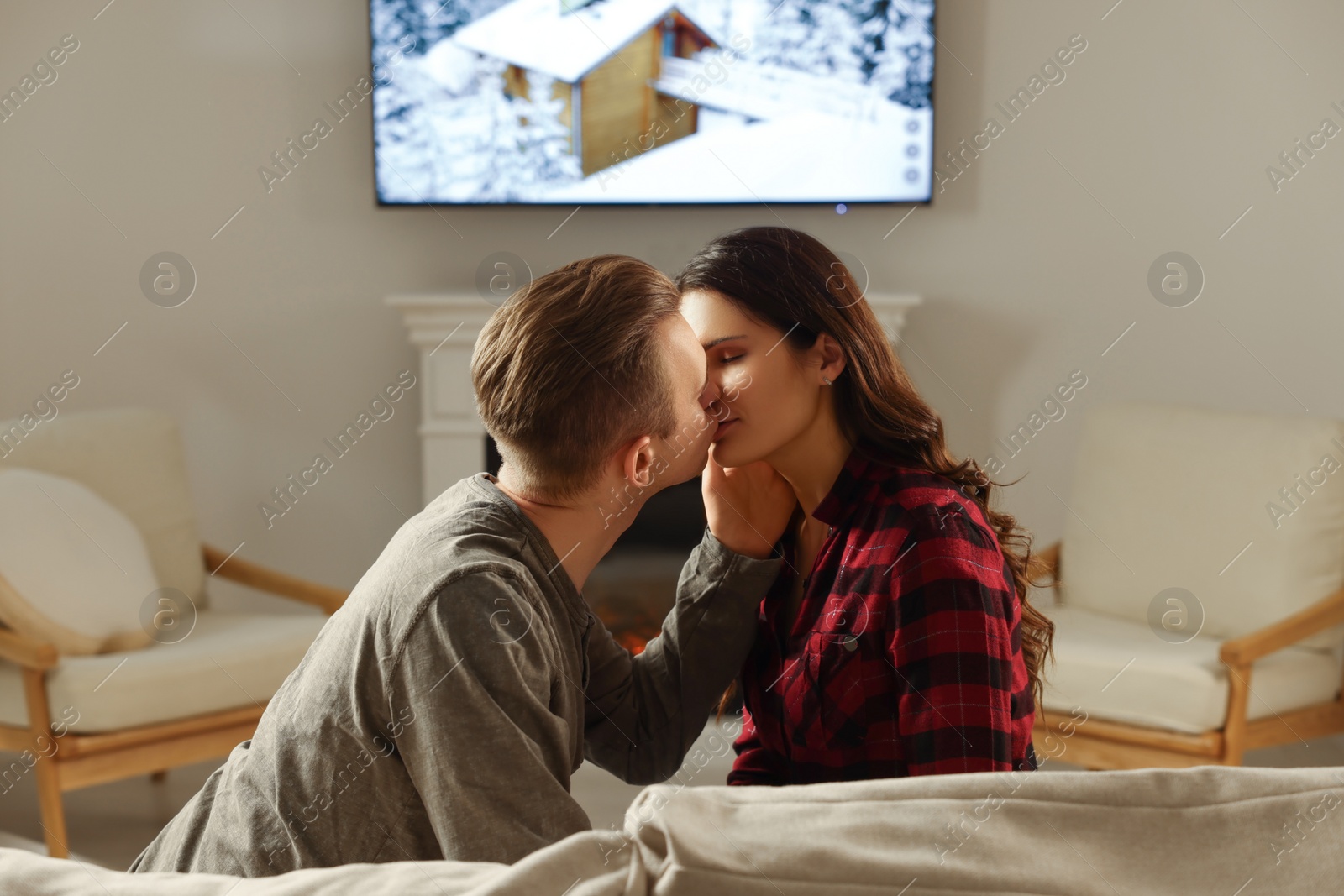 Photo of Lovely couple kissing near fireplace at home