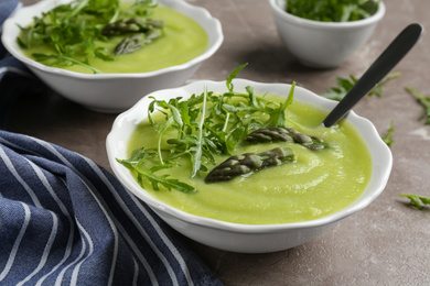Photo of Delicious asparagus soup served on grey marble table