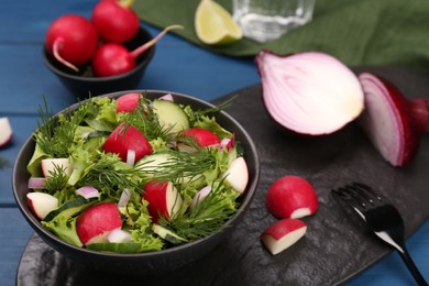 Photo of Tasty salad with radish in bowl on blue table, closeup