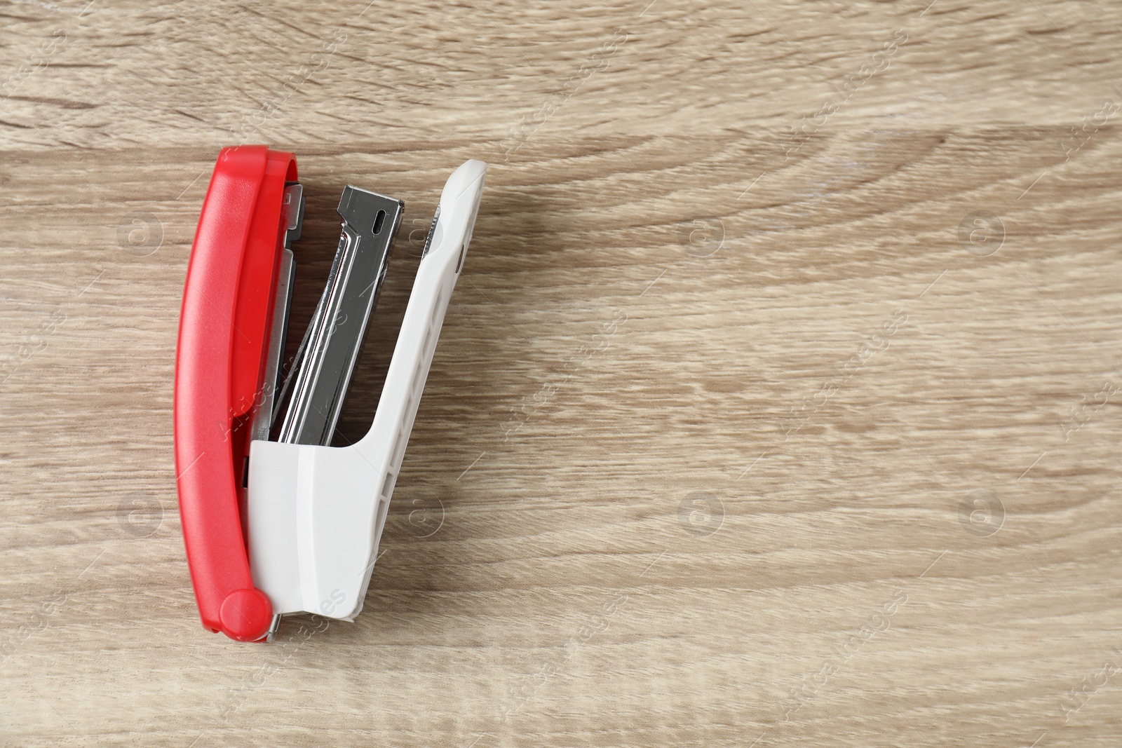 Photo of Bright stapler on wooden table, top view. Space for text