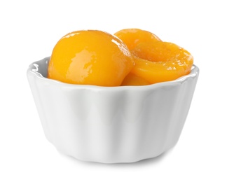 Bowl with halves of canned peaches on white background