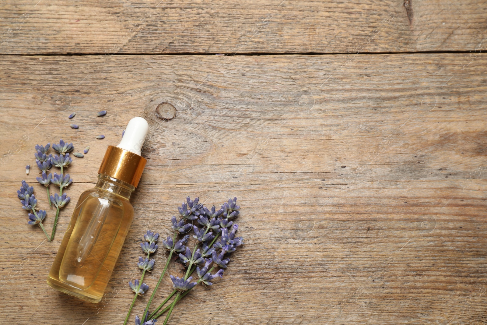 Photo of Flat lay composition with lavender flowers and natural essential oil on wooden table. Space for text