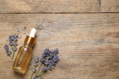 Flat lay composition with lavender flowers and natural essential oil on wooden table. Space for text