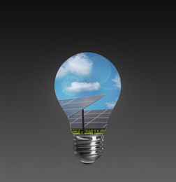 Image of Alternative energy source. Light bulb with solar panels on dark background 