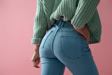 Woman wearing jeans on pink background, closeup