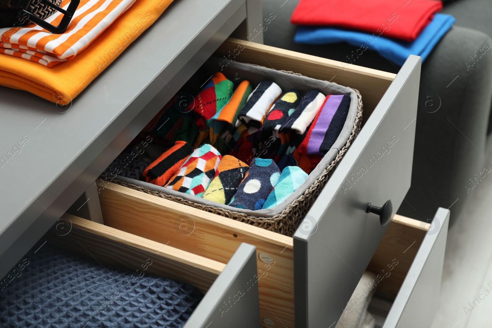 Photo of Chest of drawers with different folded clothes indoors, closeup