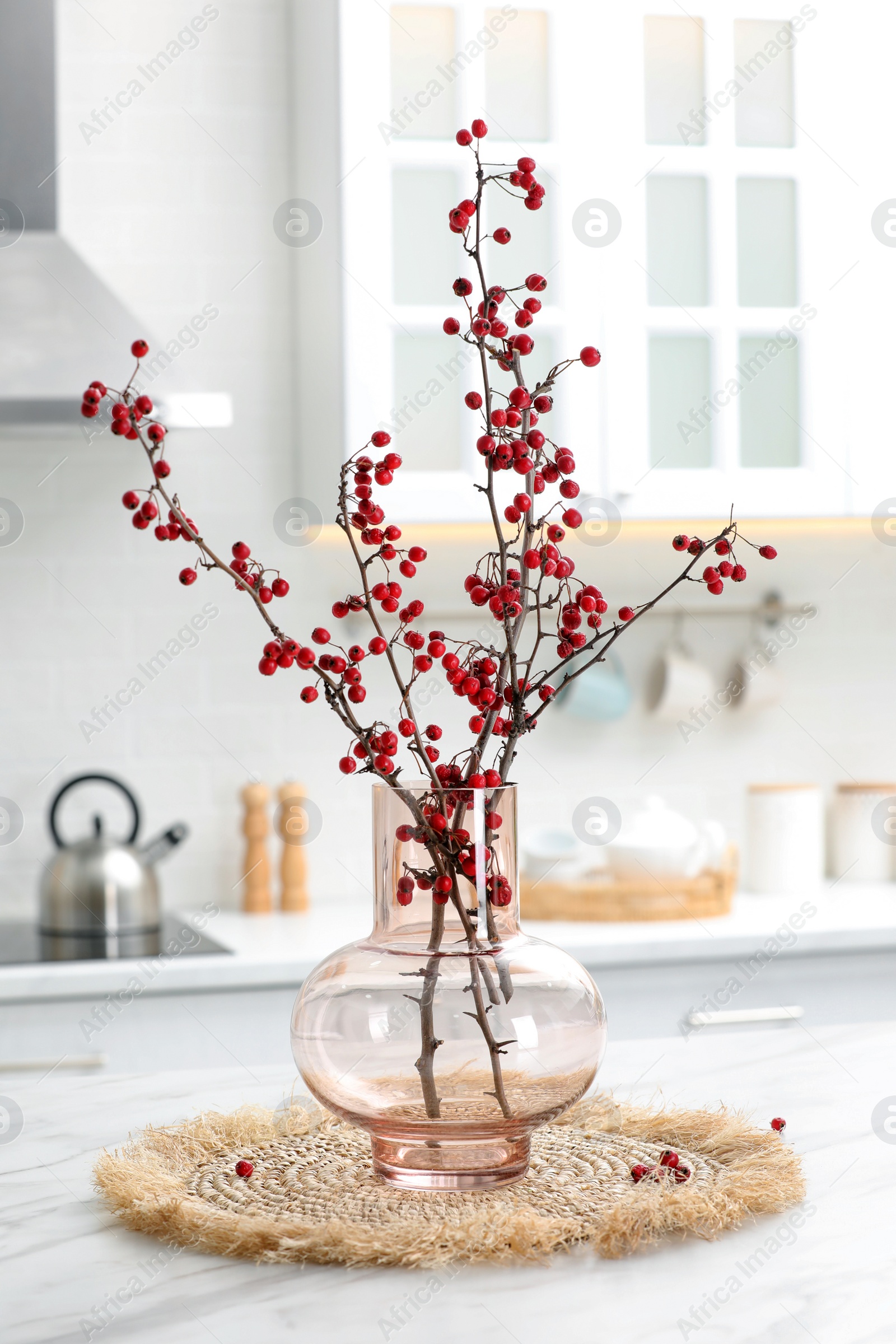 Photo of Hawthorn branches with red berries on table in kitchen