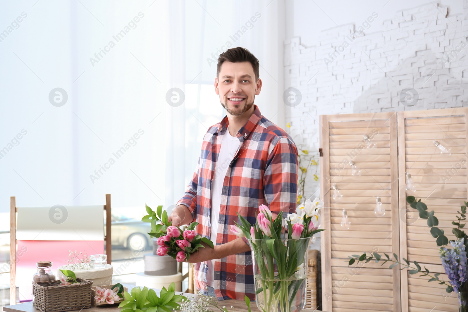 Photo of Male decorator creating beautiful bouquet at table