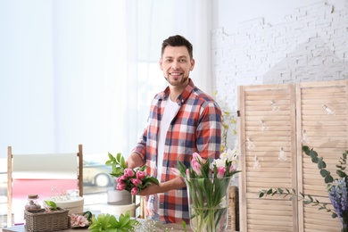 Male decorator creating beautiful bouquet at table