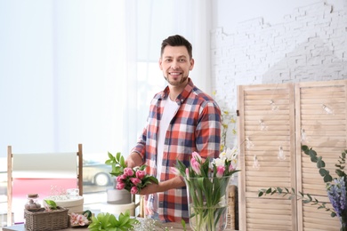 Photo of Male decorator creating beautiful bouquet at table