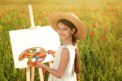 Photo of Little girl painting on easel in beautiful poppy field