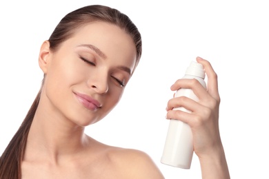 Photo of Young woman applying thermal water on face against white background. Cosmetic product