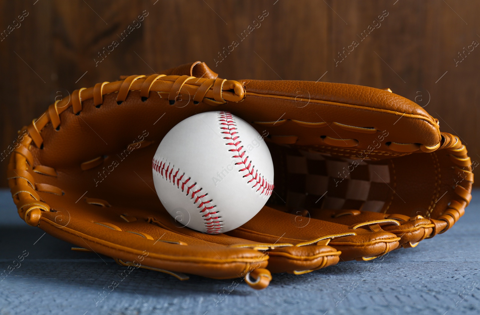 Photo of Leather baseball glove with ball on grey wooden table