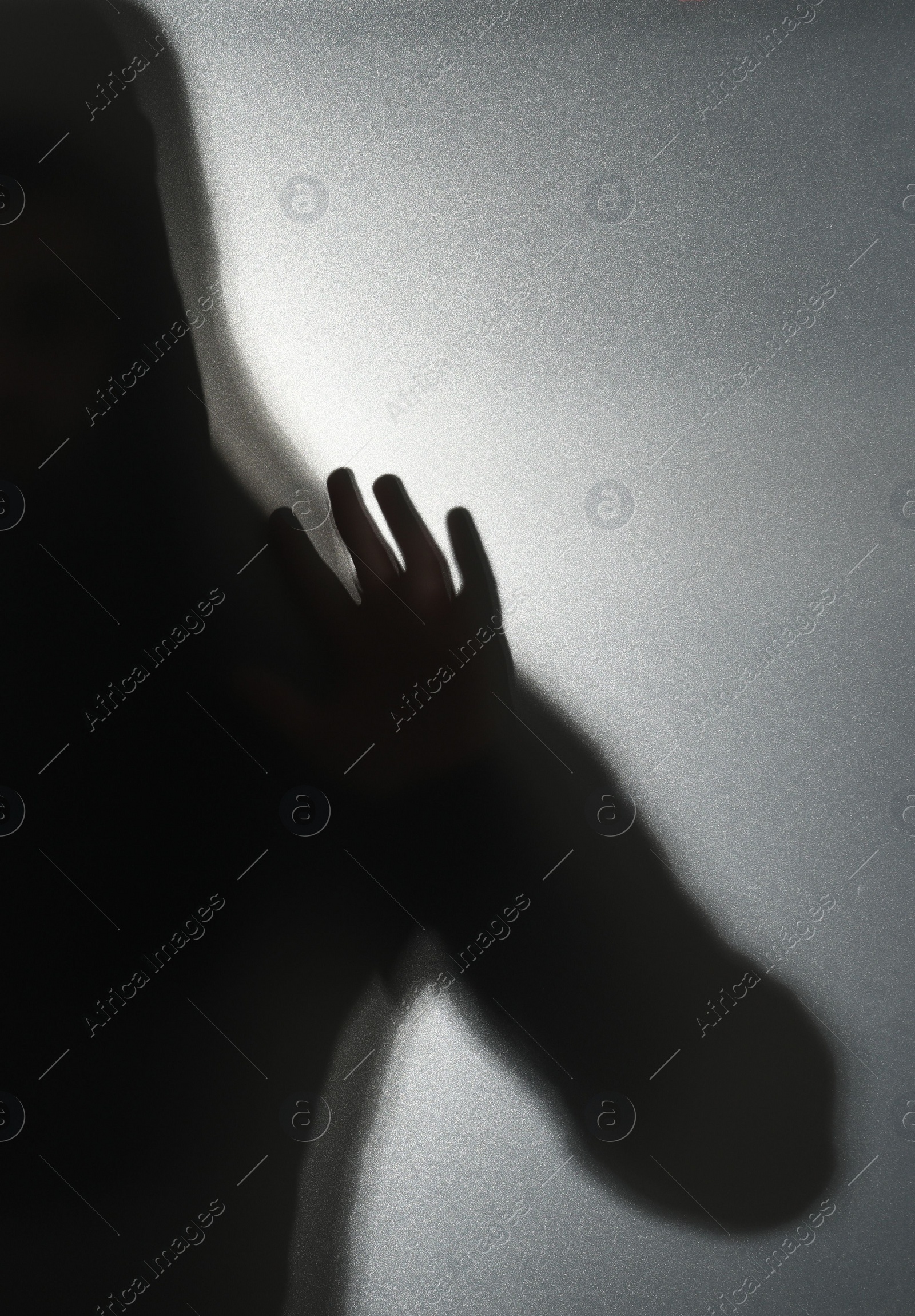 Photo of Silhouette of ghost behind glass against grey background