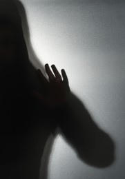 Silhouette of ghost behind glass against grey background