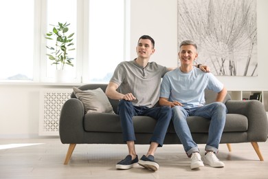 Photo of Happy men sitting on sofa at home