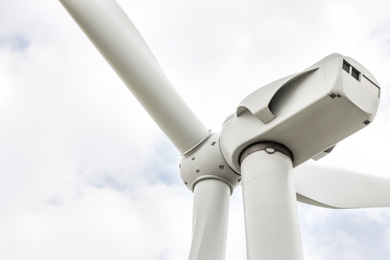 Photo of Modern wind turbine against cloudy sky, closeup. Alternative energy source