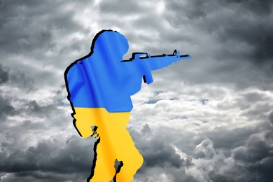 Image of Silhouette of soldier in color of Ukrainian flag with assault rifle against cloudy sky