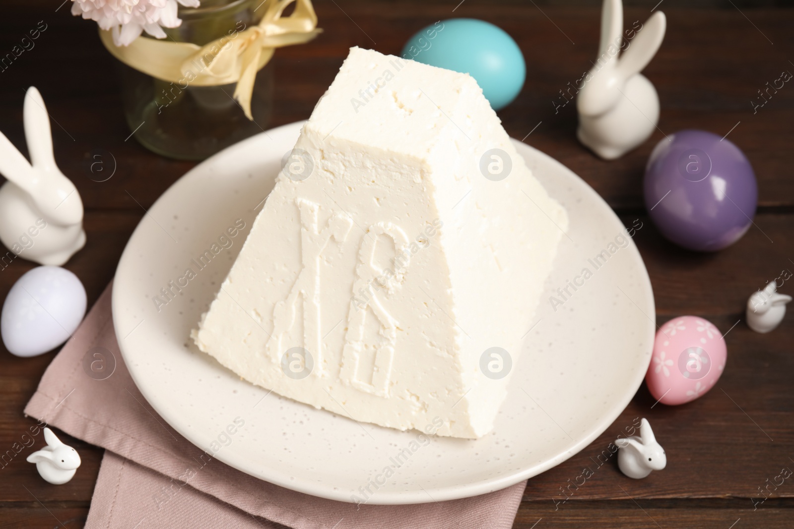 Photo of Traditional cottage cheese Easter paskha, painted eggs and decorative bunnies on wooden table