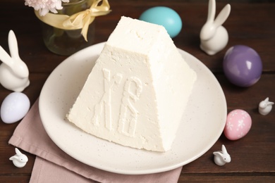 Photo of Traditional cottage cheese Easter paskha, painted eggs and decorative bunnies on wooden table