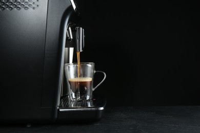 Photo of Making coffee with modern espresso machine on grey table against black background. Space for text