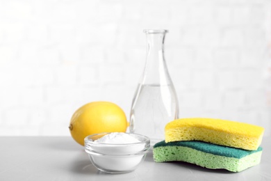 Baking soda, lemon, vinegar and sponges on light grey table