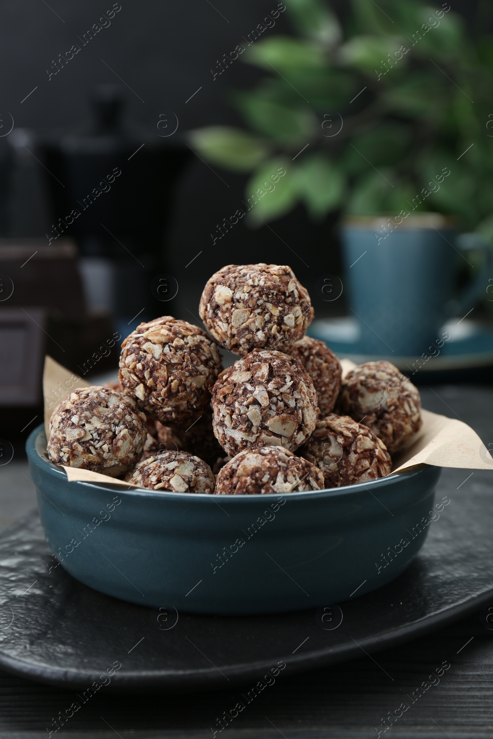 Photo of Bowl of delicious sweet chocolate candies on black table